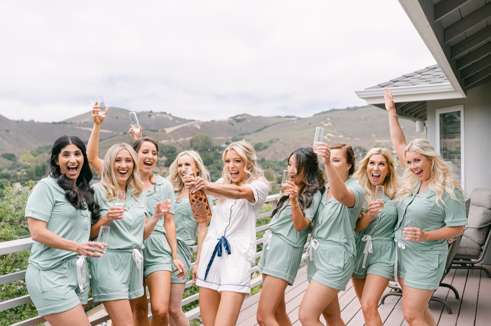 A bride and her bridal party celebrating while getting ready on a hillside deck
